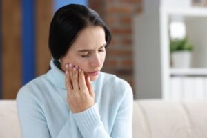 woman holding her sore jaw 